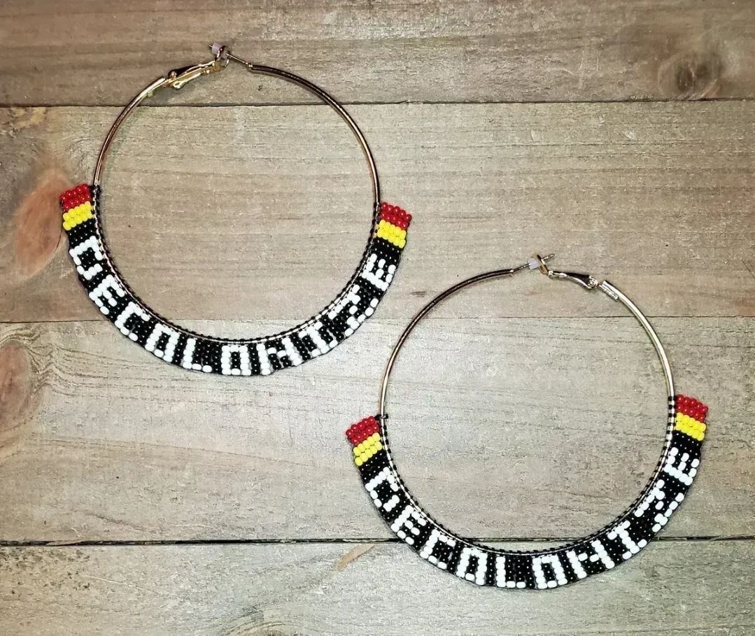 silver-tone hoop earrings with black, white, red, and yellow beads that say DECOLONIZE