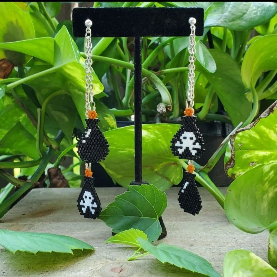 beaded earrings made with black and white Mikyuki Delicas, 2 poison bottles on each earrings hanging from silver chains, with a green plant background