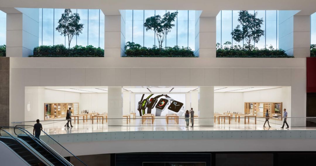 A modern Apple Store entrance with a large glass facade and a prominent Apple logo.