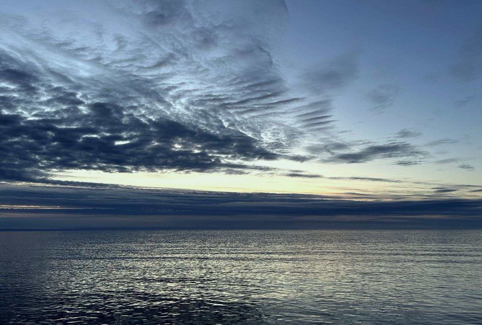 Weiter Horizont, ruhiges Wasser, dunkler Himmel in kühlen Farben.