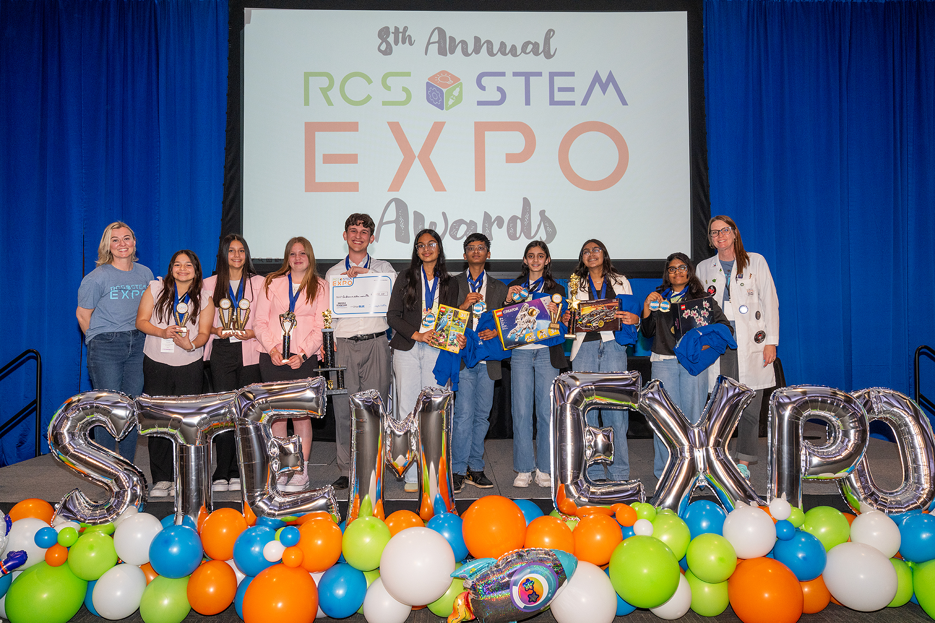Students posing on stage with their awards and teachers at the 8th Annual RCS STEM Expo Awards