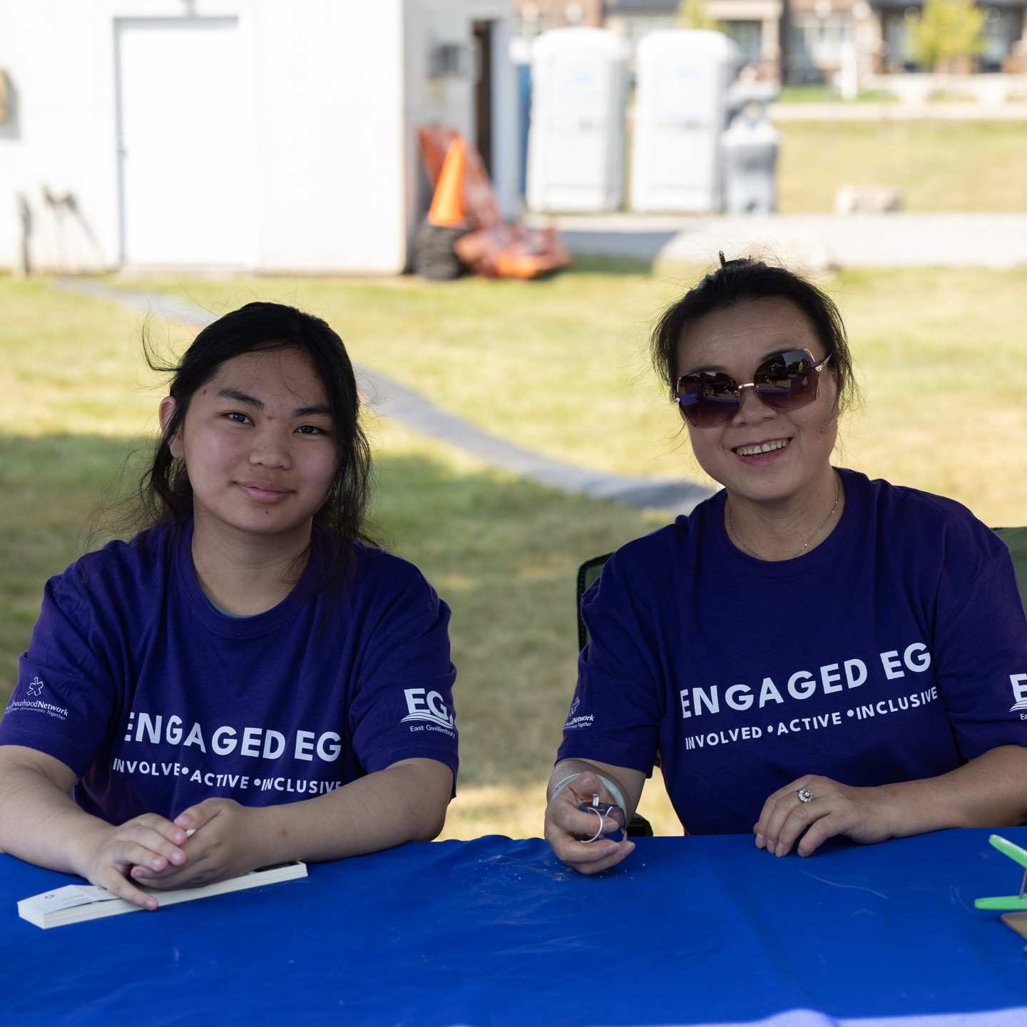 Two people sitting at a table wearing Engaged EG shirts. 