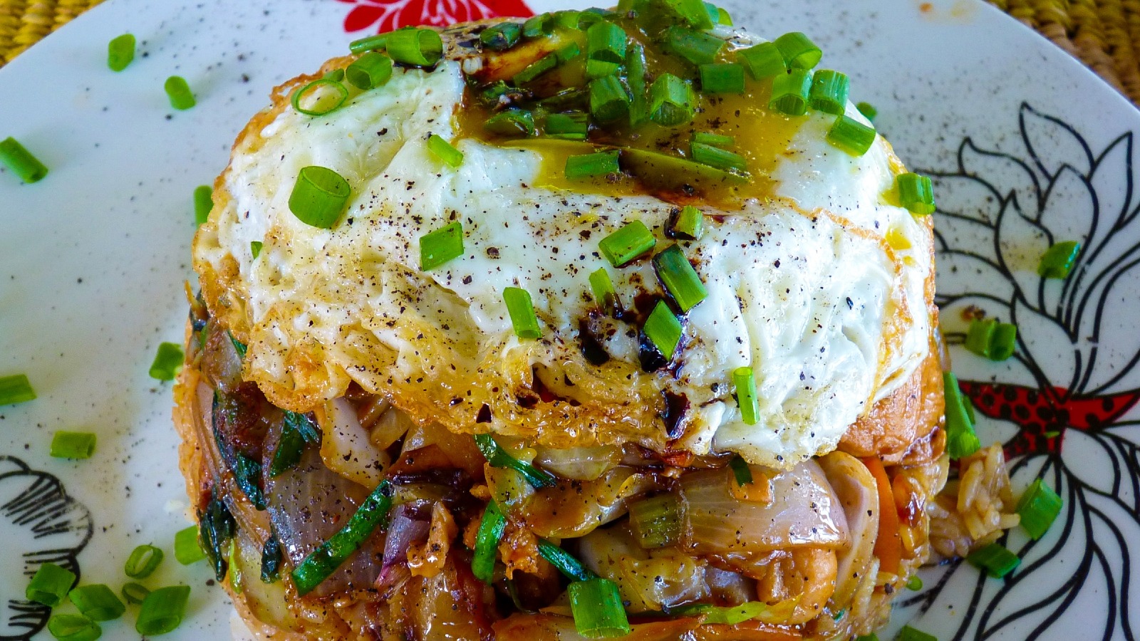 Un cuenco invertido, plato típico de Mauricio, un montículo con arroz, verduras salteadas y huevo frito de yema líquida, decorado con cebollino picado.