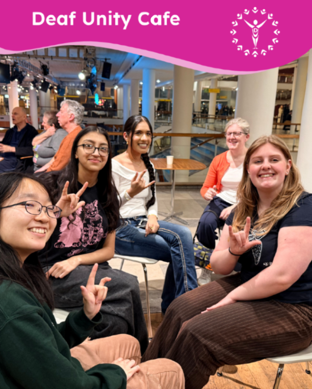 Smiling group seated at Deaf Unity Cafe