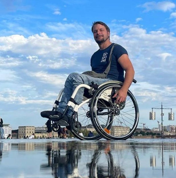 Selfie - ich im Rollstuhl, Vorderräder leicht in der Luft, spiegelnder Hintergrund