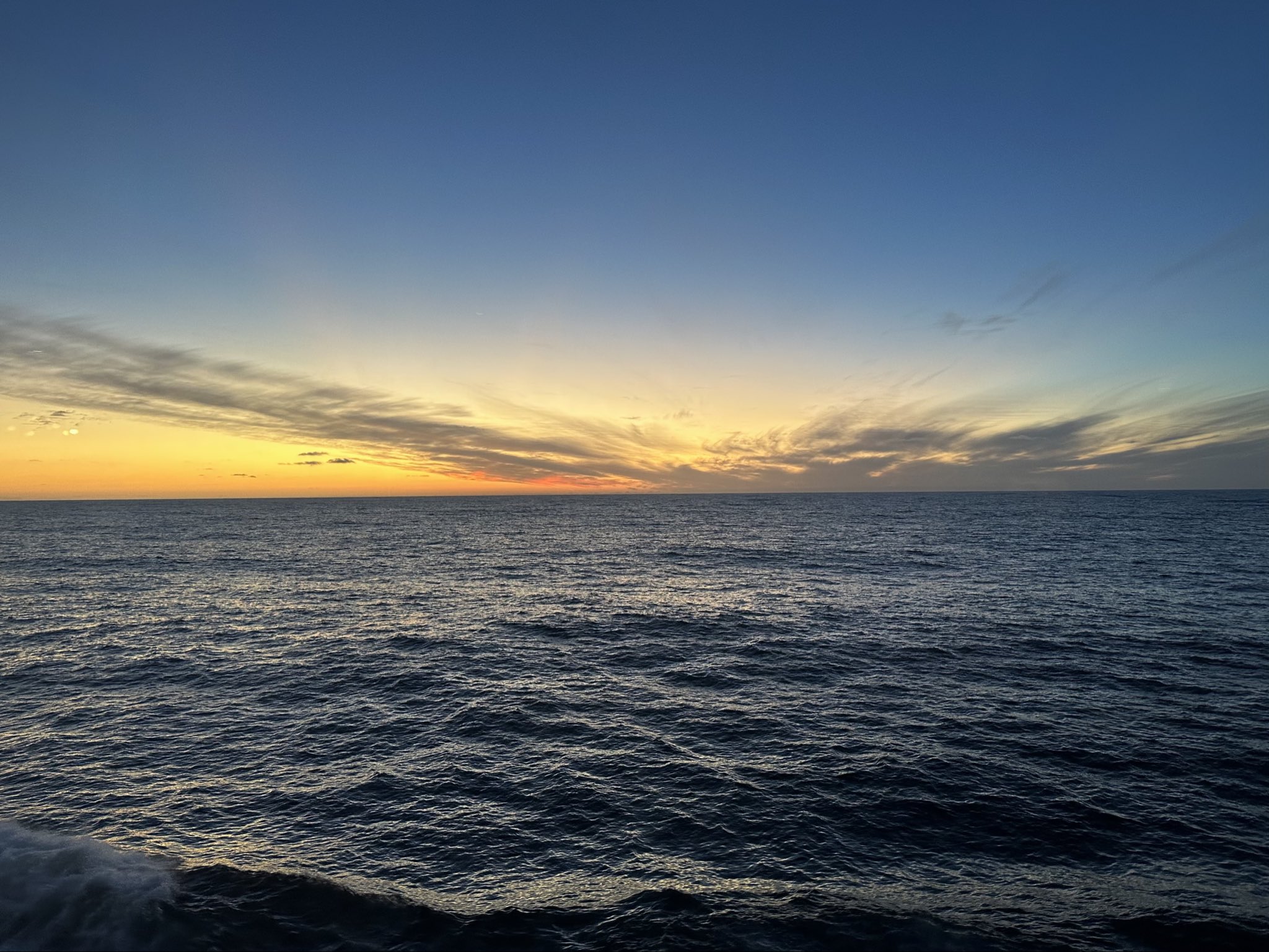 Sonnenuntergang über dem Meer, ruhige Wellen, weiter Horizont, Himmel in warmen und kühlen Farbverläufen