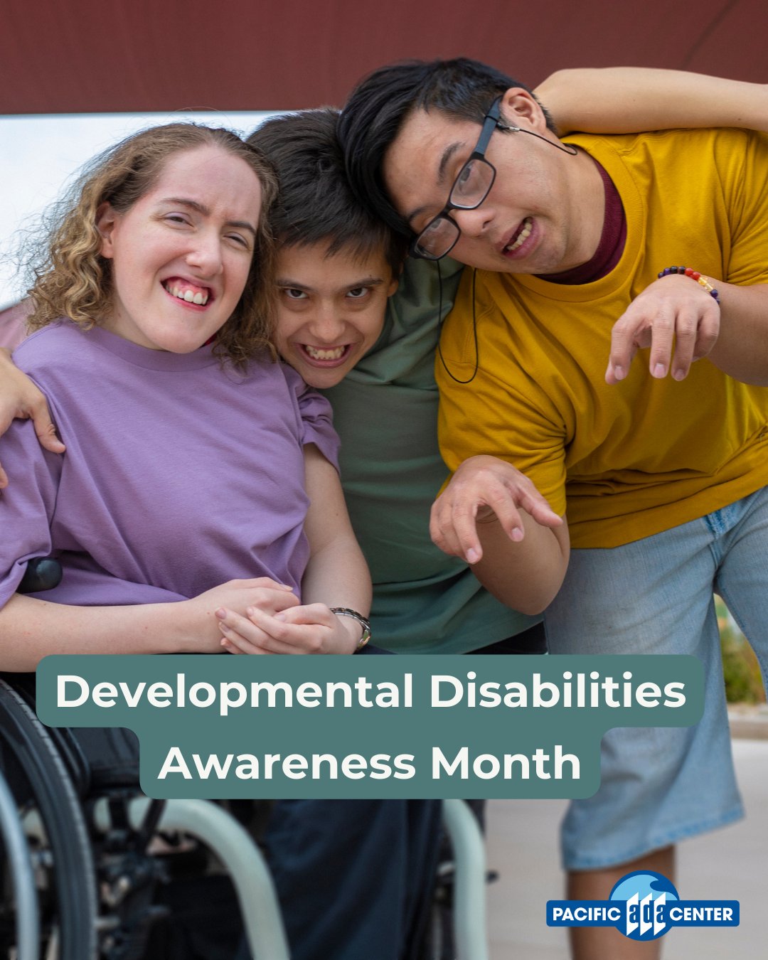 Three friends smiling and embracing, promoting Developmental Disabilities Awareness Month with a wheelchair visible in the foreground.
