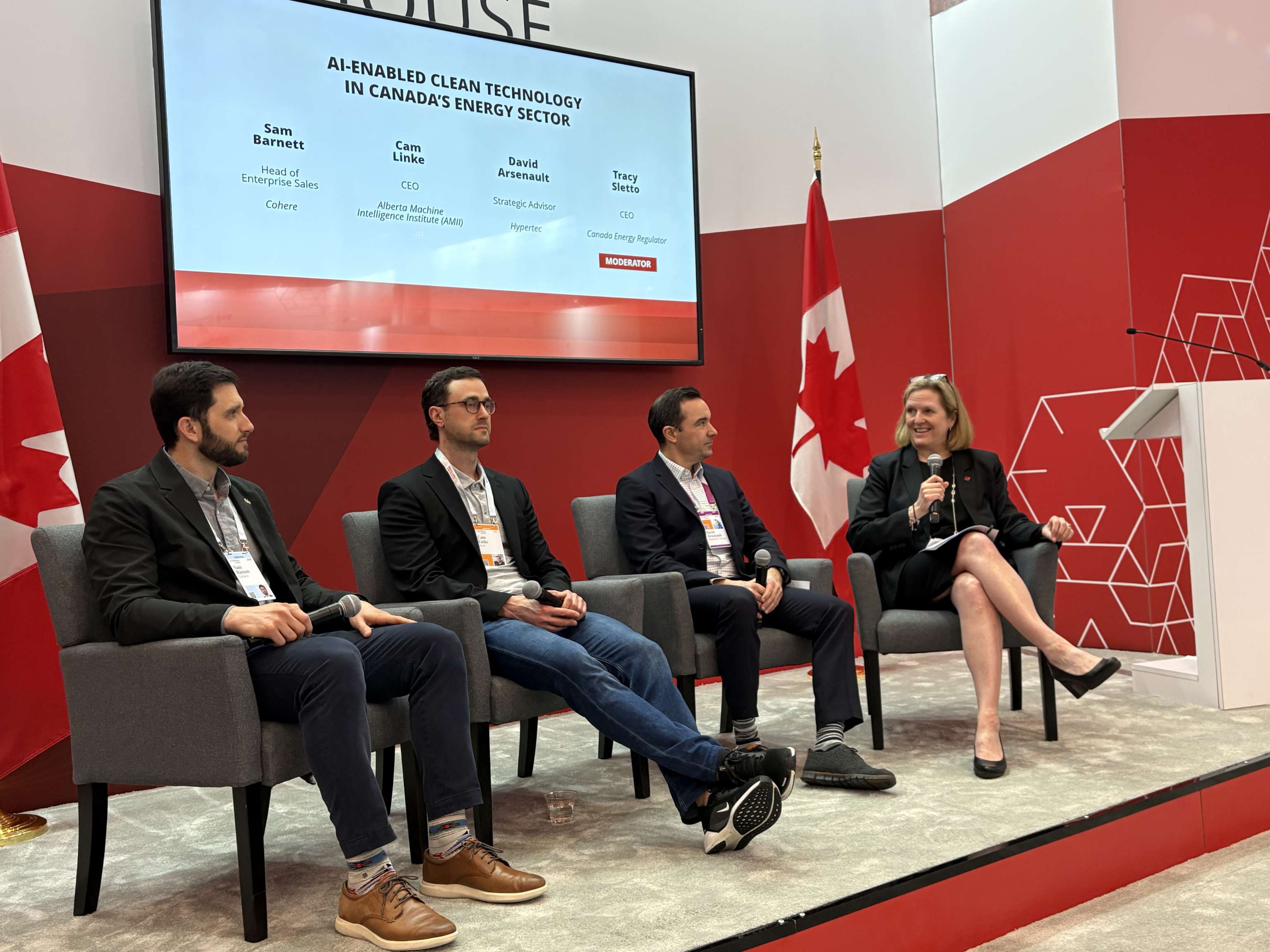 A panel of four people speaking with red and white background.