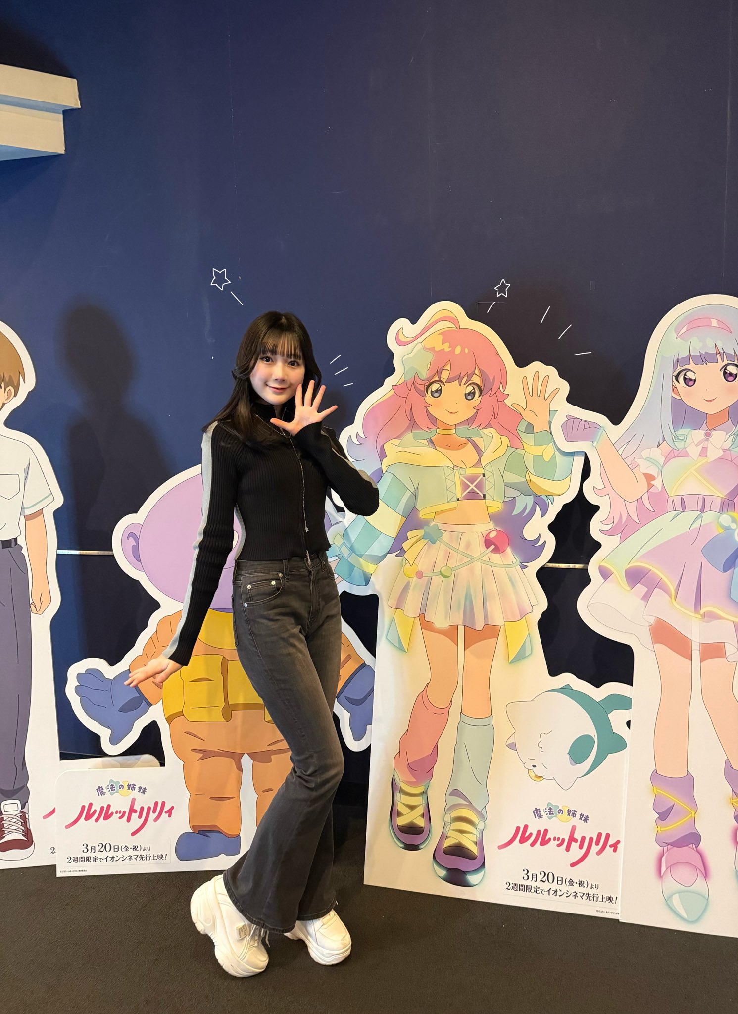 イオンシネマのシアター前廊下に展示してあるルルットリリィの等身大パネルに並んだ橘めいの他撮り写真。
こんぺとリリィのポーズを真似て左手を顔横でパーにしています。右手はおろして手のひらを地面と平行にしています。右膝を曲げ、左脚に寄せています。
口を閉じるタイプの笑顔です。
黒地に灰色のラインが袖と脇下に入ったタイトなトップスに暖かめのグレーのフレアデニム、白いスニーカーを着用しています。
橘が被ってしまっておりますが、リリィの左隣にミーター、翔太、画面右隣にルルのパネルもあります。