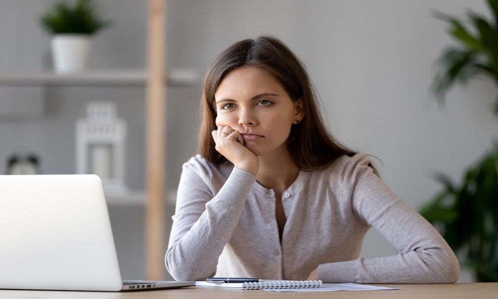 Woman sat at laptop looking bored