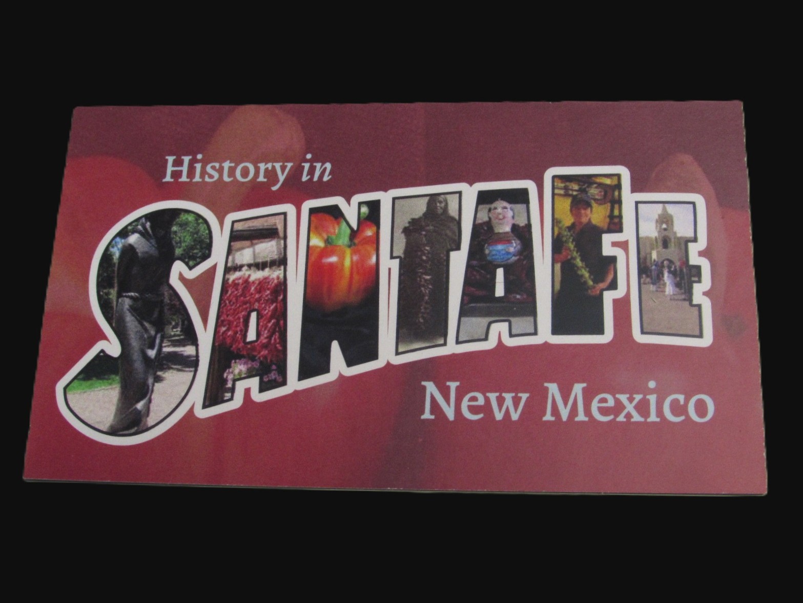 A red card on a black background with the words "History in Santa Fe New Mexico". Inside the letters of Santa Fe are different photos of a statue, a chile ristra, a chile pepper, an old photo, and other Santa Fe emblems.