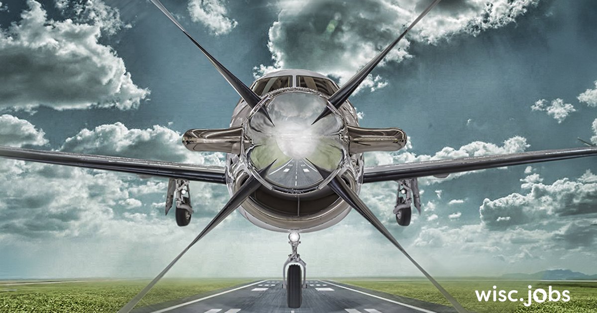 Image: front view of a sleek propeller airplane on a runway under a cloudy sky; Wisc.Jobs