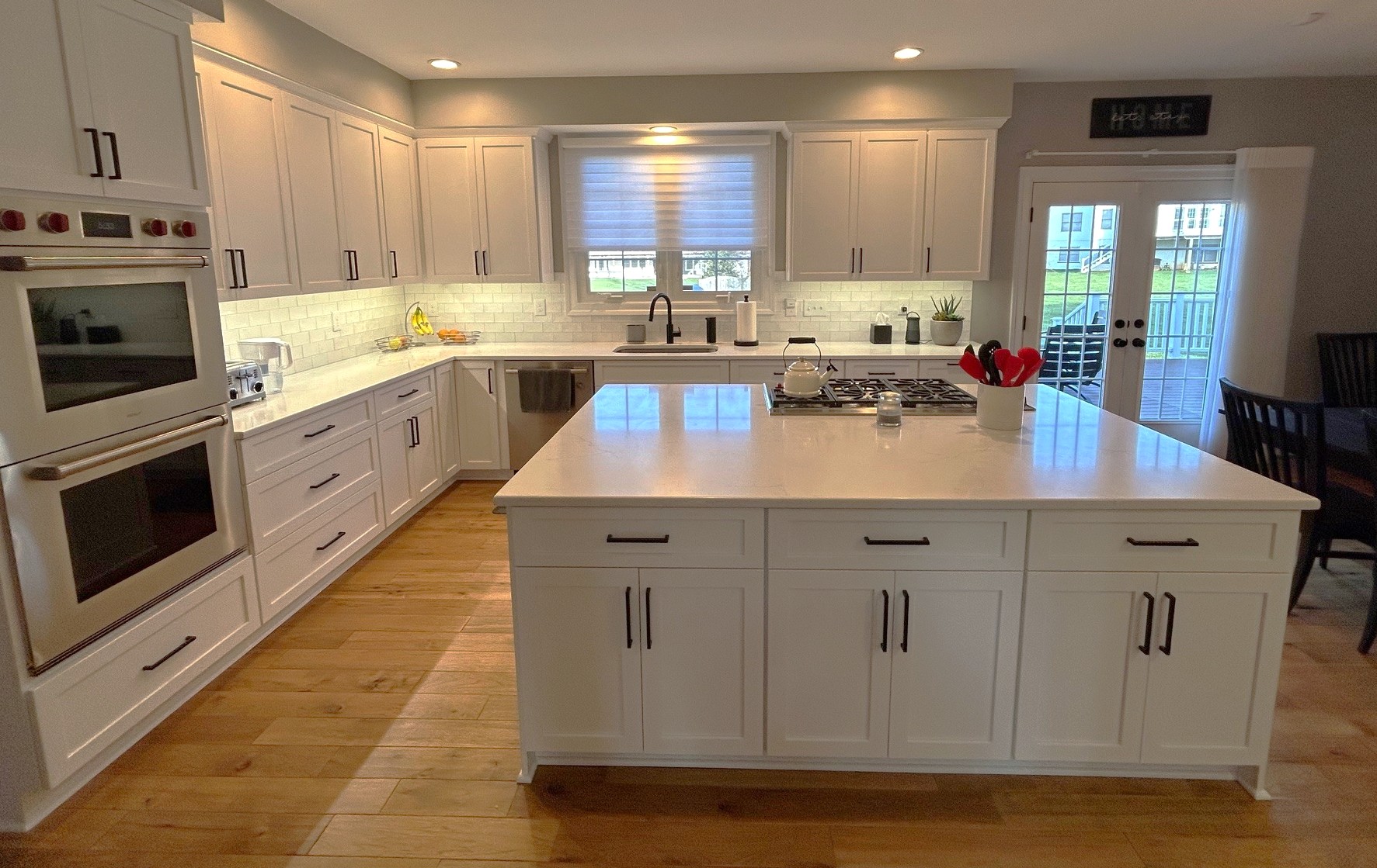 A Transitional Kitchen Transformation in Olney, MD
We recently completed this stunning kitchen remodel in Olney, MD, blending the best of contemporary and traditional design elements for a truly functional and beautiful space.
Clean Lines and Clever Details
This transitional kitchen features white Shaker-style cabinetry that provides a timeless foundation. We paired the classic cabinets with sleek, matte black hardware for a modern, industrial touch. To create a bright and open feel, we installed white subway tile backsplashes with under-cabinet LED lighting that highlights the stunning polished quartz countertops.
A Focus on Function
The expansive center island is designed for maximum utility. It features a flush-mounted gas cooktop and plenty of extra storage, making it the perfect hub for both meal prep and entertaining. For added convenience, we integrated a dedicated beverage station with a wine cooler and ample counter space for a coffee bar.
Ready to transform your kitchen?