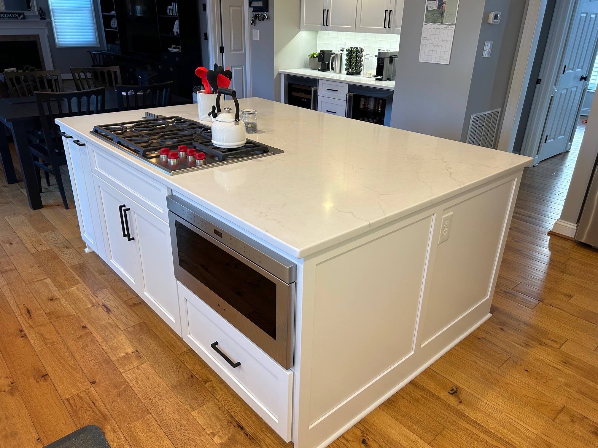 This kitchen remodel by Talon Construction Inc. in Olney showcases a transitional design that balances clean, modern lines with a warm, inviting atmosphere. The space is anchored by a large, multi-functional center island and a bright, monochromatic color palette