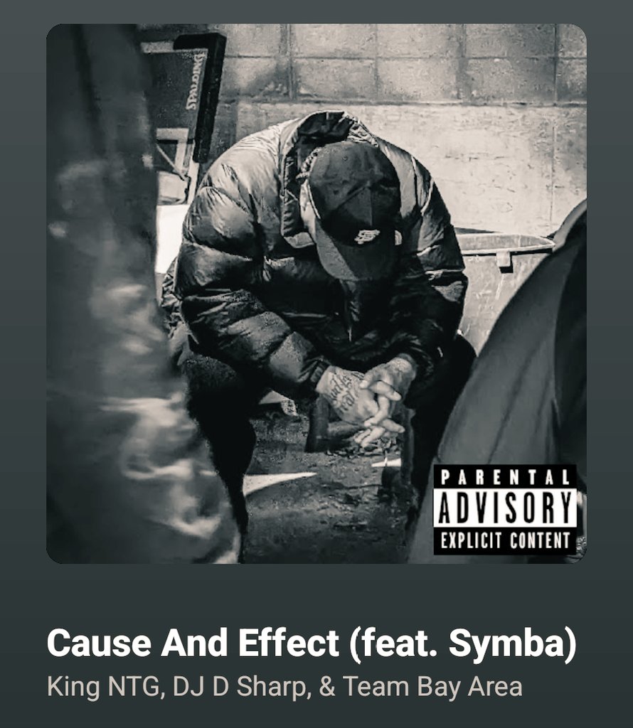 Black and white photo of a man in a puffer jacket and SF hat, head down in a gritty urban setting. 