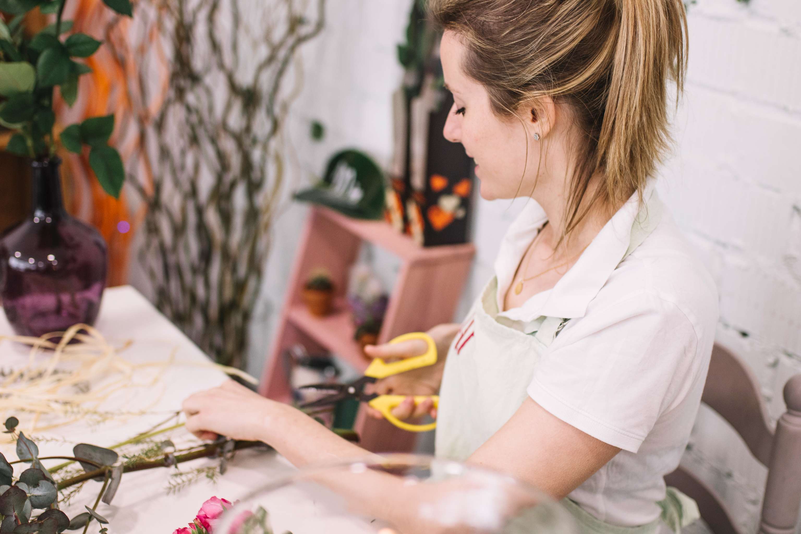 Una dona tallant una flor en una floristeria.