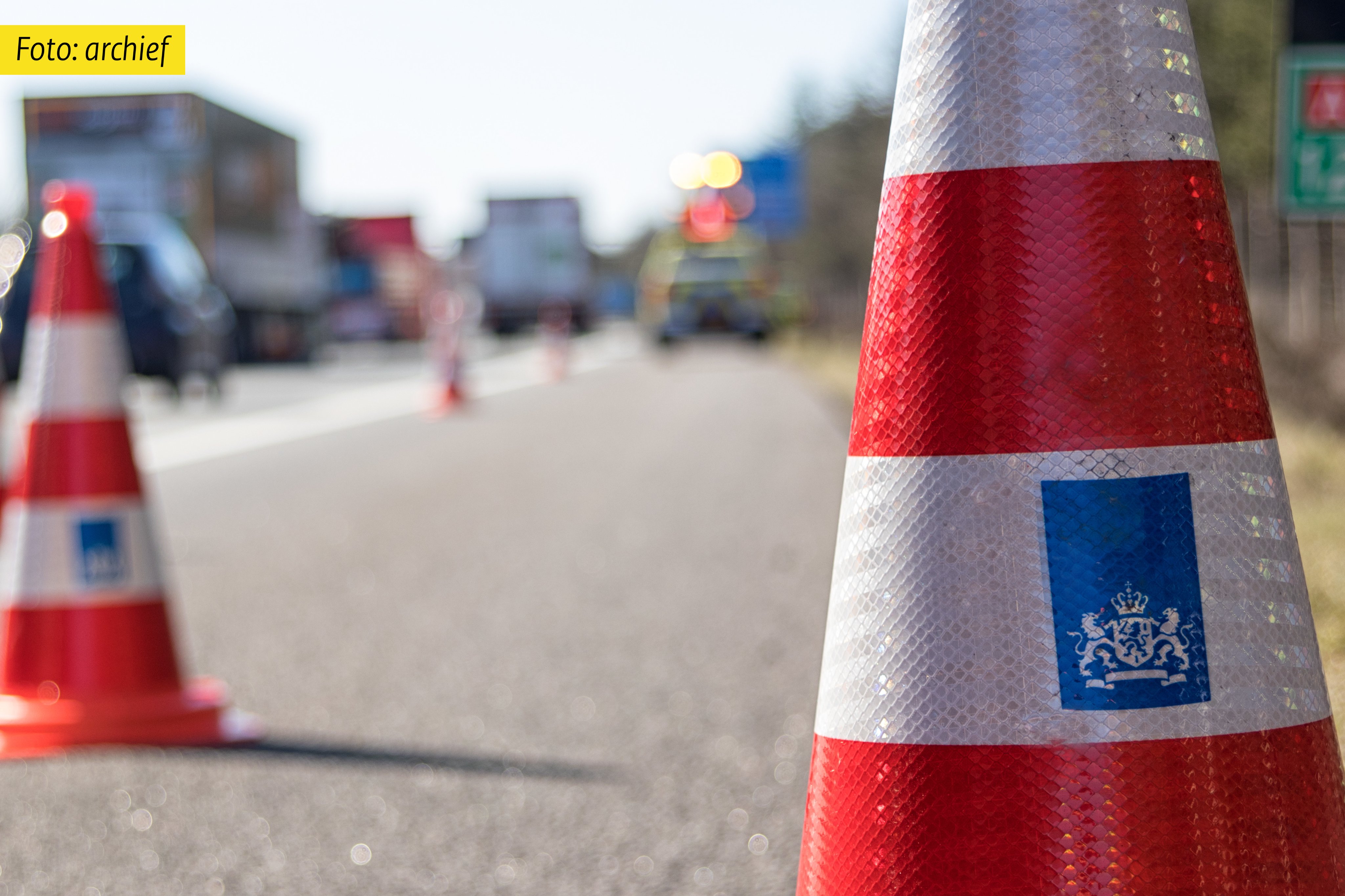 Archieffoto van kegels op de weg en in de achtergrond onscherp een auto van een weginspecteur