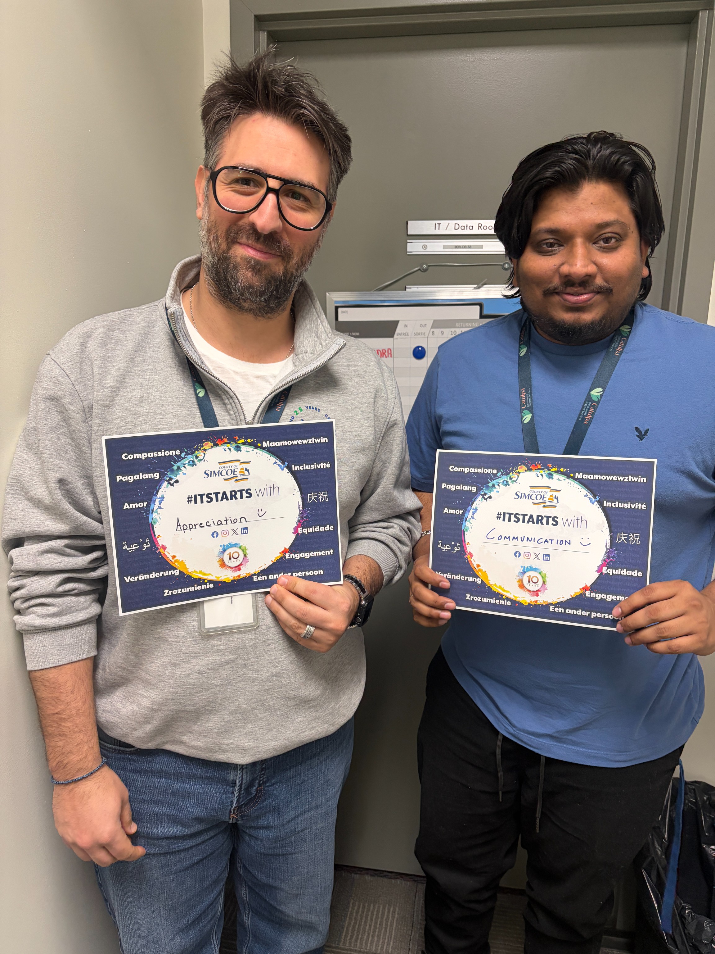 Two men standing indoors holding ITSTARTS cards that say '#ITSTARTS with Appreciation' with various positive words around the border.