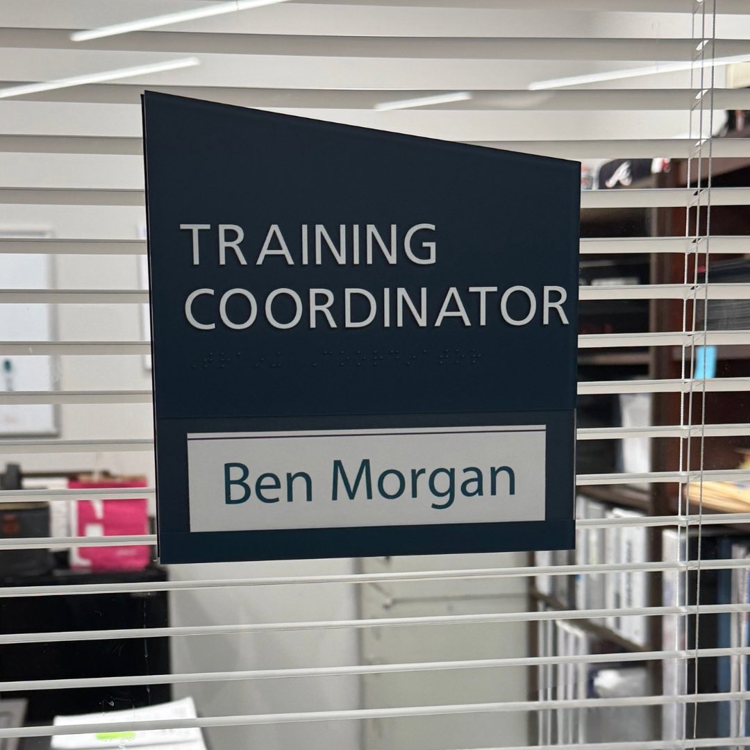 An office nameplate that reads, "Ben Morgan" attached to a glass door.