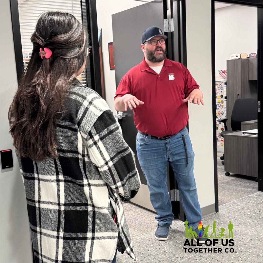 A male professional standing, talking to a female professional. Company logo positioned right in footer.