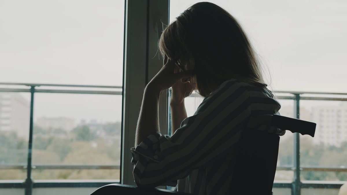 Una persona en silla de ruedas delante de la ventana. 
