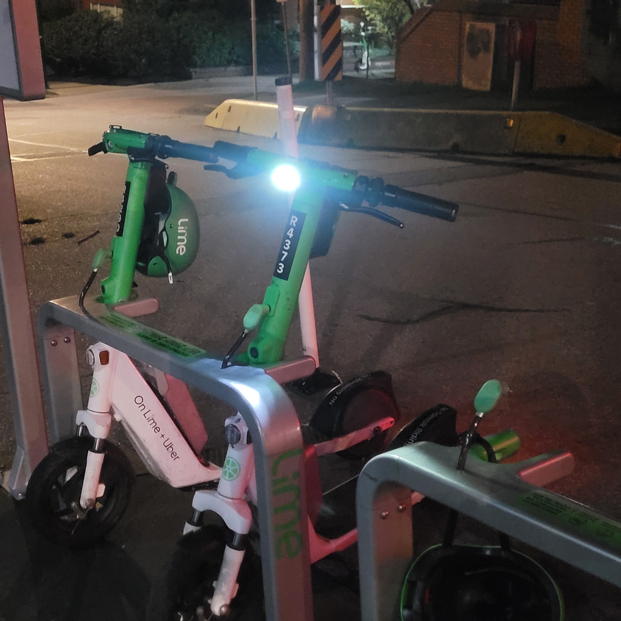 Lime e-scooter docked on Alder St still has it's headlamp on.