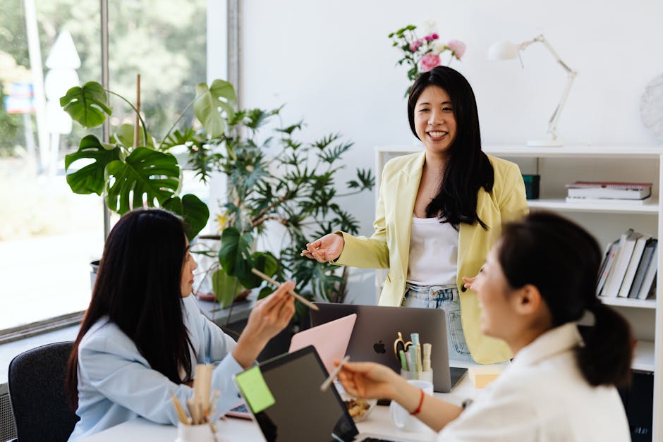 Three women engage in a lively brainstorming session in a modern office setting.