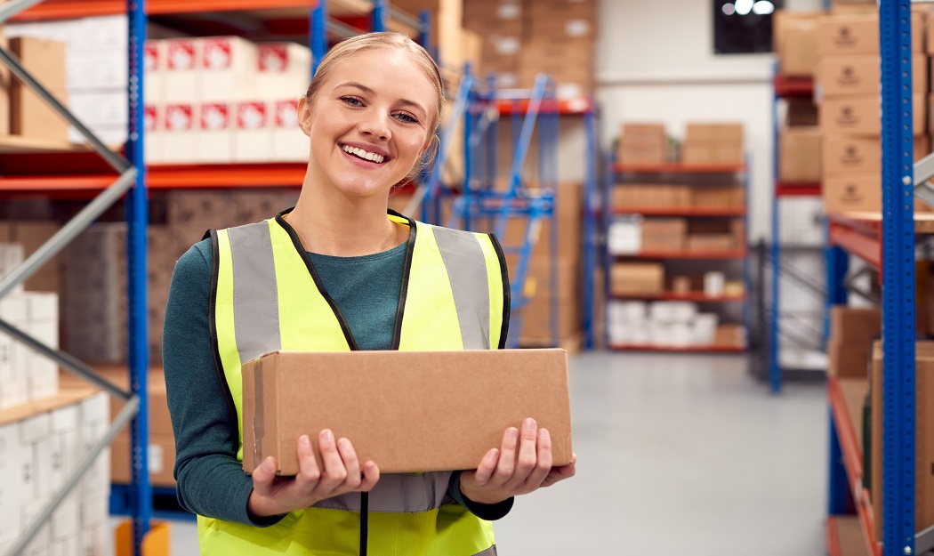 Girl working in a warehouse holding a box