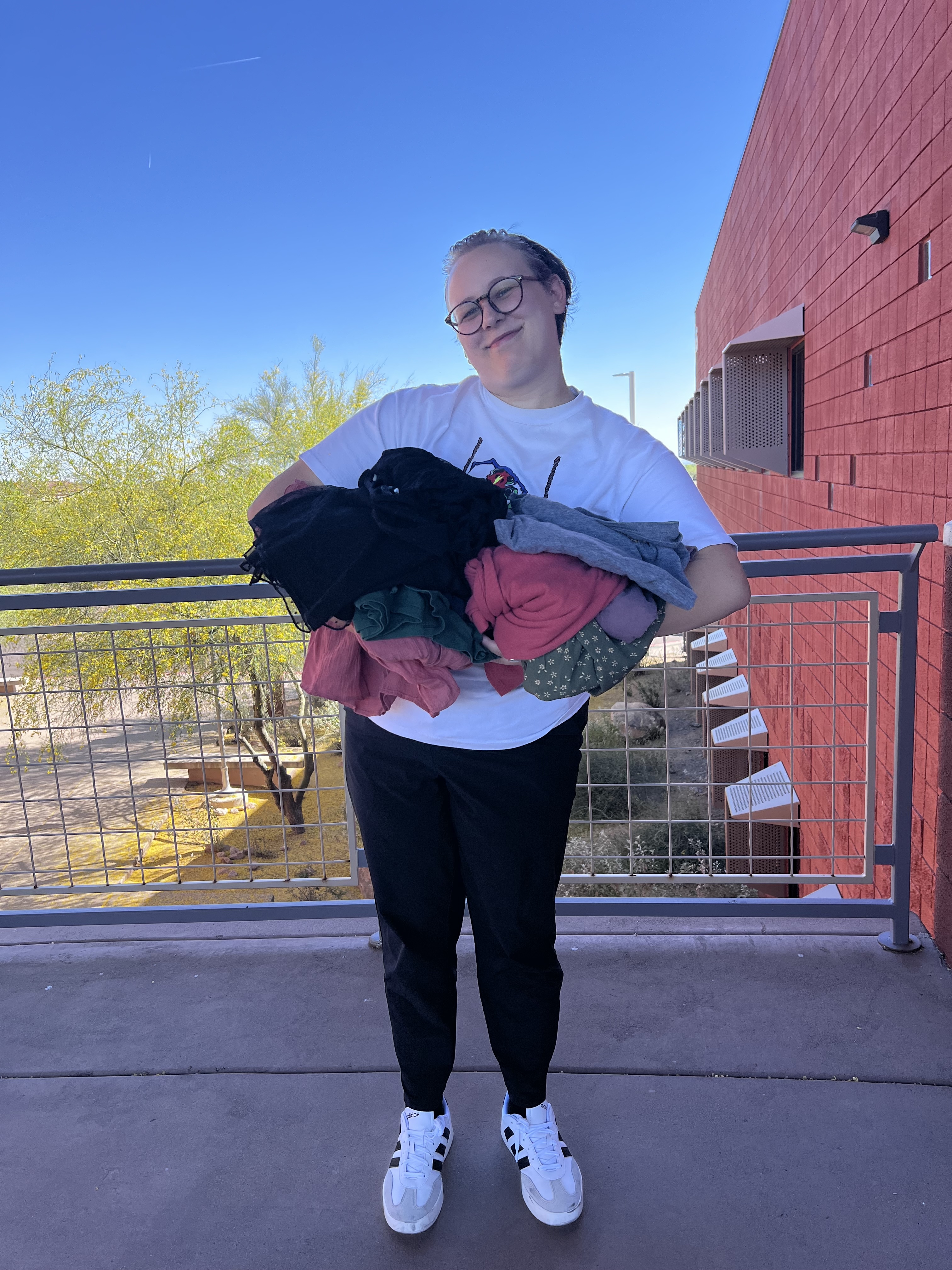 Individual smiling with clothes donation in hand.