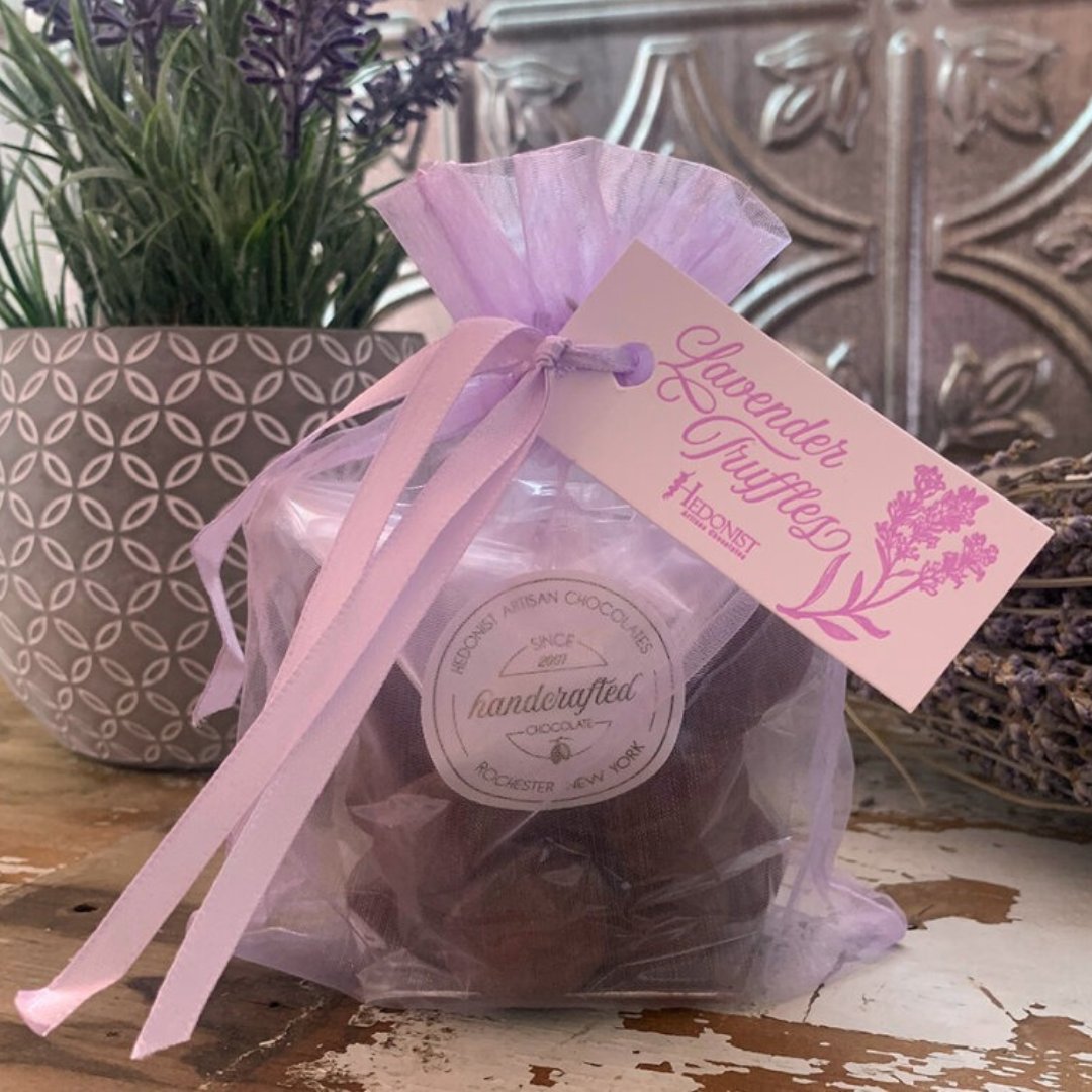 Purple organza gift bag with ribbon holding handcrafted chocolate truffles and a "Lavender Truffles" tag beside lavender