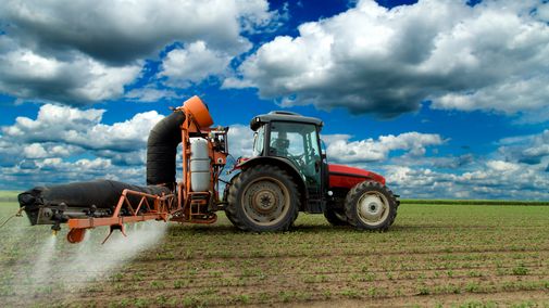 Tractor applying herbicide to soybean field