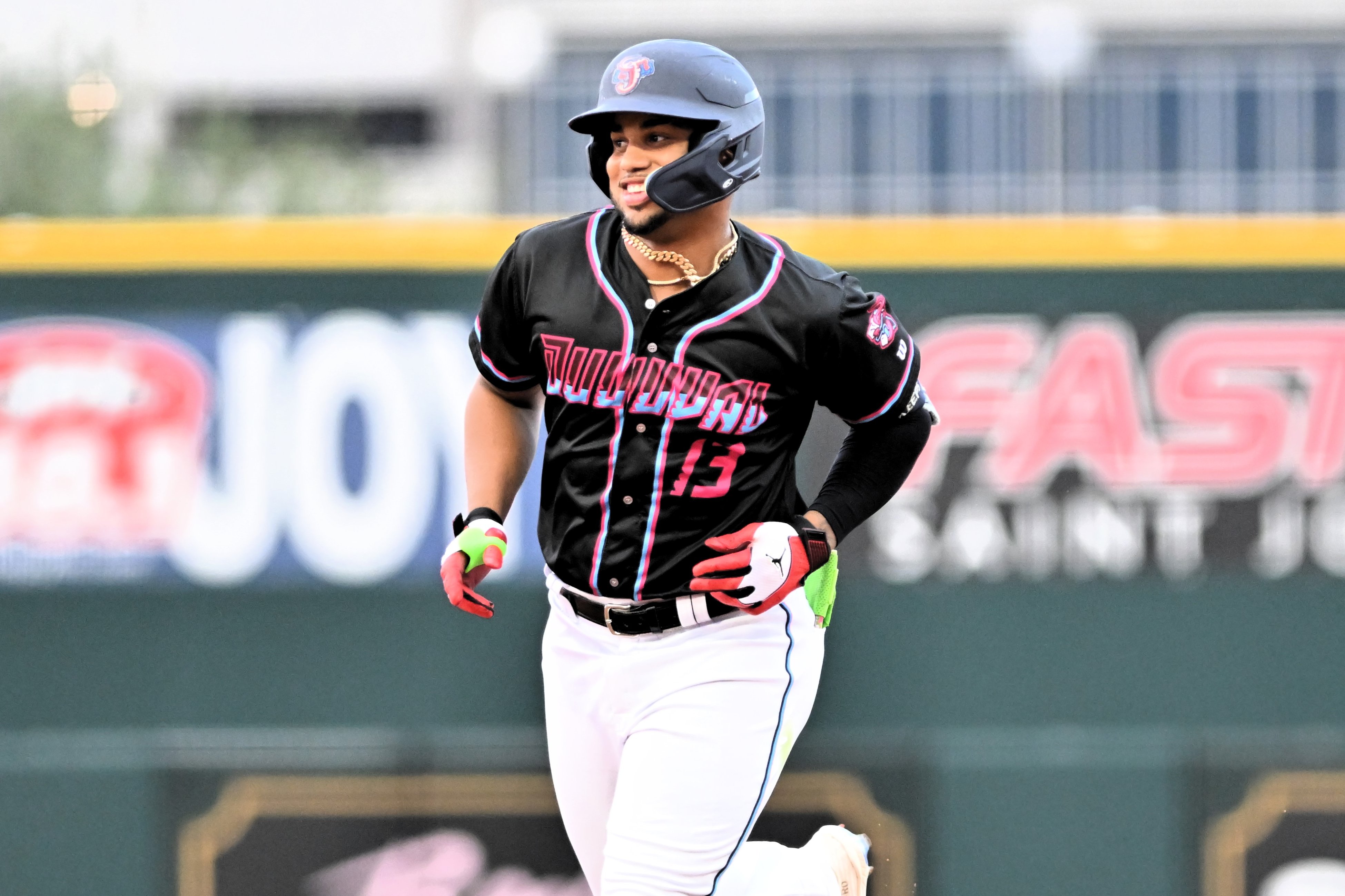 Deyvison De Los Santos smiles while wearing a black helmet and black uniform top with pink trim.