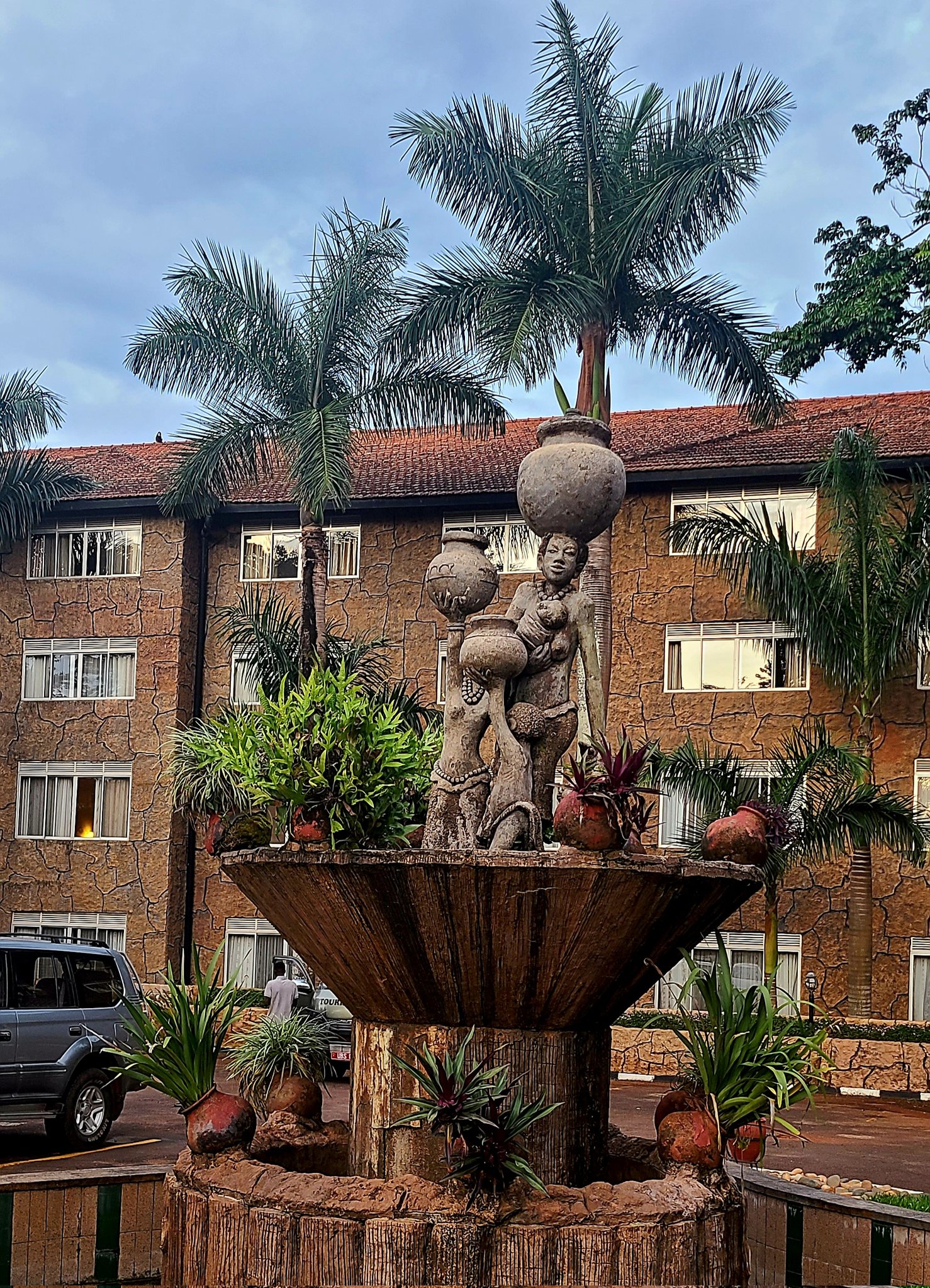 A sculpture of a mother carrying a large pot of water on her head, with a baby in one hand. She has a daughter and a son along with her both carrying pots and directing them to her.