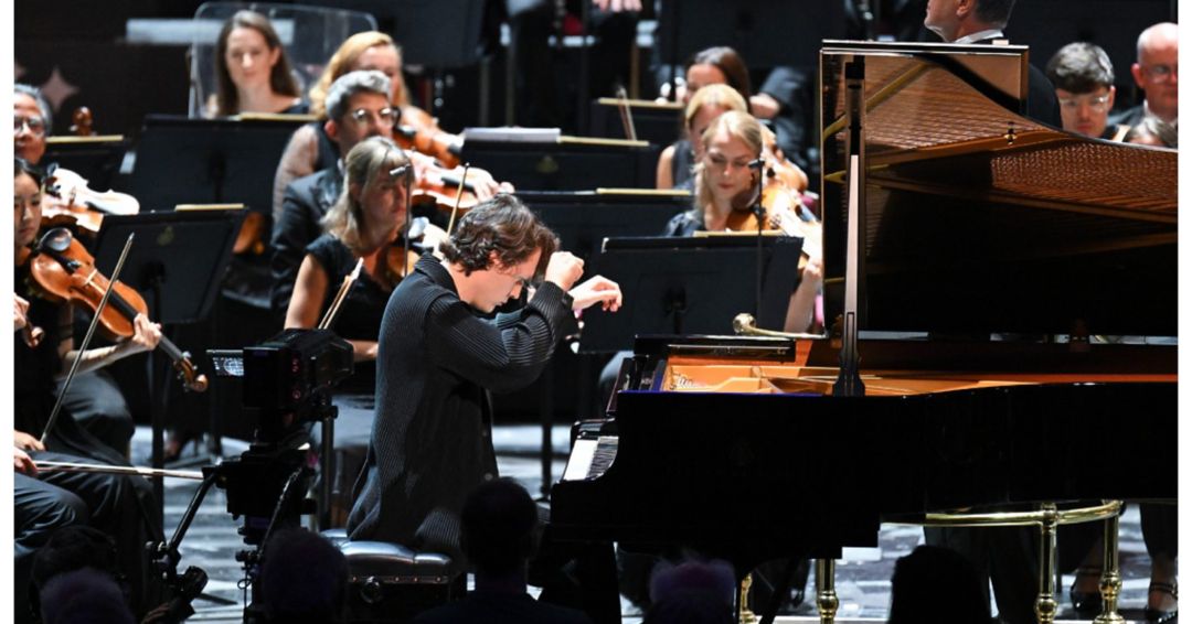 A classical music concert featuring a pianist and orchestra on a grand stage, viewed through Apple Vision Pro.