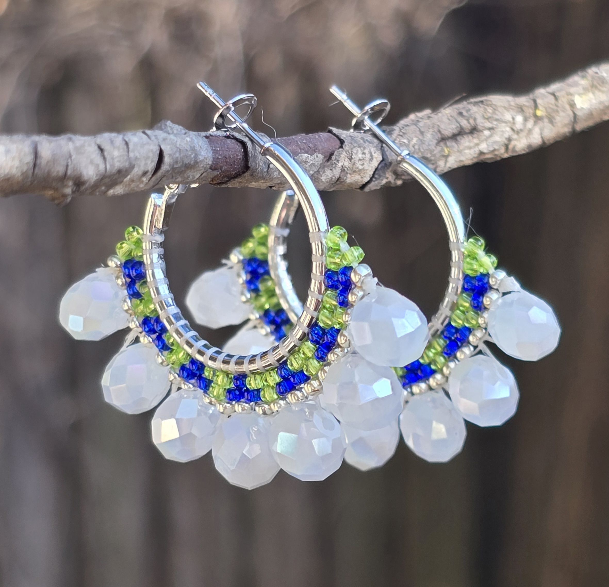 silver-tone hoop earrings inspired by Seattle Seahawks team colors, glass beads in shades of blue, lime green, and white, background of natural woods