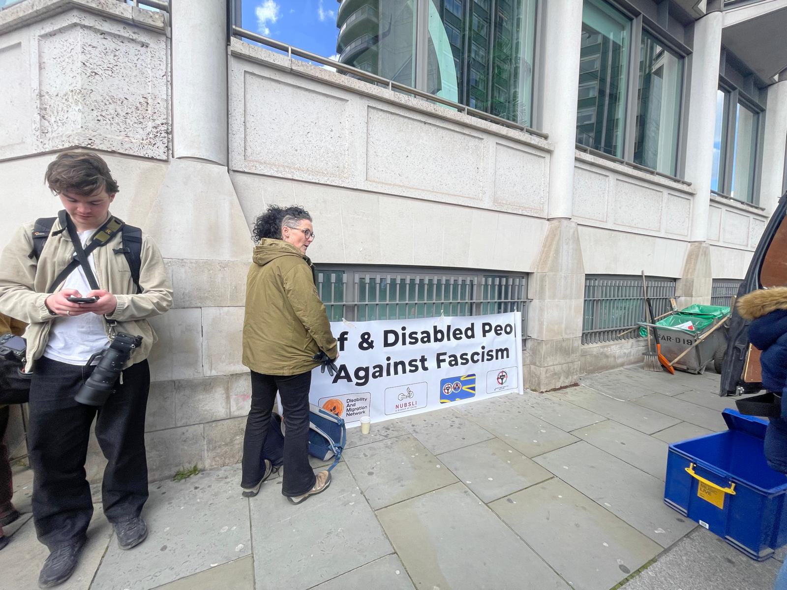 Image shows activists near the Deaf and disabled people bloc banner getting ready to march