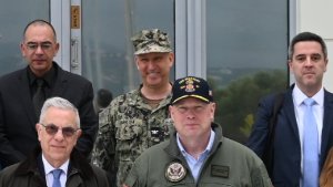 Image, cropped, from: https://x.com/NMIOTC/status/2036404945541288121, showing the incumbent US defense attaché to Greece, USN captain Mark Imblum, facing front & smiling, in combat uniform

The relevant Tuesday 24 March 2026 @NMIOTC tweet reads:
"🇺🇸 On Thursday, 19 March 2026, the Permanent Representative of the United States to #NATO, H.E. Ambassador Matthew G. Whitaker visited NMIOTC in the context of his official visit to  🇬🇷.
"@USAmbNATO @Hellenic_MOD @GreeceNATO @USEmbassyAthens"

NMIOTC:
"NATO Maritime Interdiction Operational Training Centre (NMIOTC) is a training facility for NATO, at Crete Naval Base, in Souda Bay, Crete, Greece.
"Located at the Northern Sector of the base (Marathi), it enables the NATO forces to better execute surface, sub-surface, aerial surveillance, and special operations activities that are necessary for the support of Maritime Interdiction Operations (MIO)."
https://en.wikipedia.org/wiki/NATO_Maritime_Interdiction_Operational_Training_Centre
+++