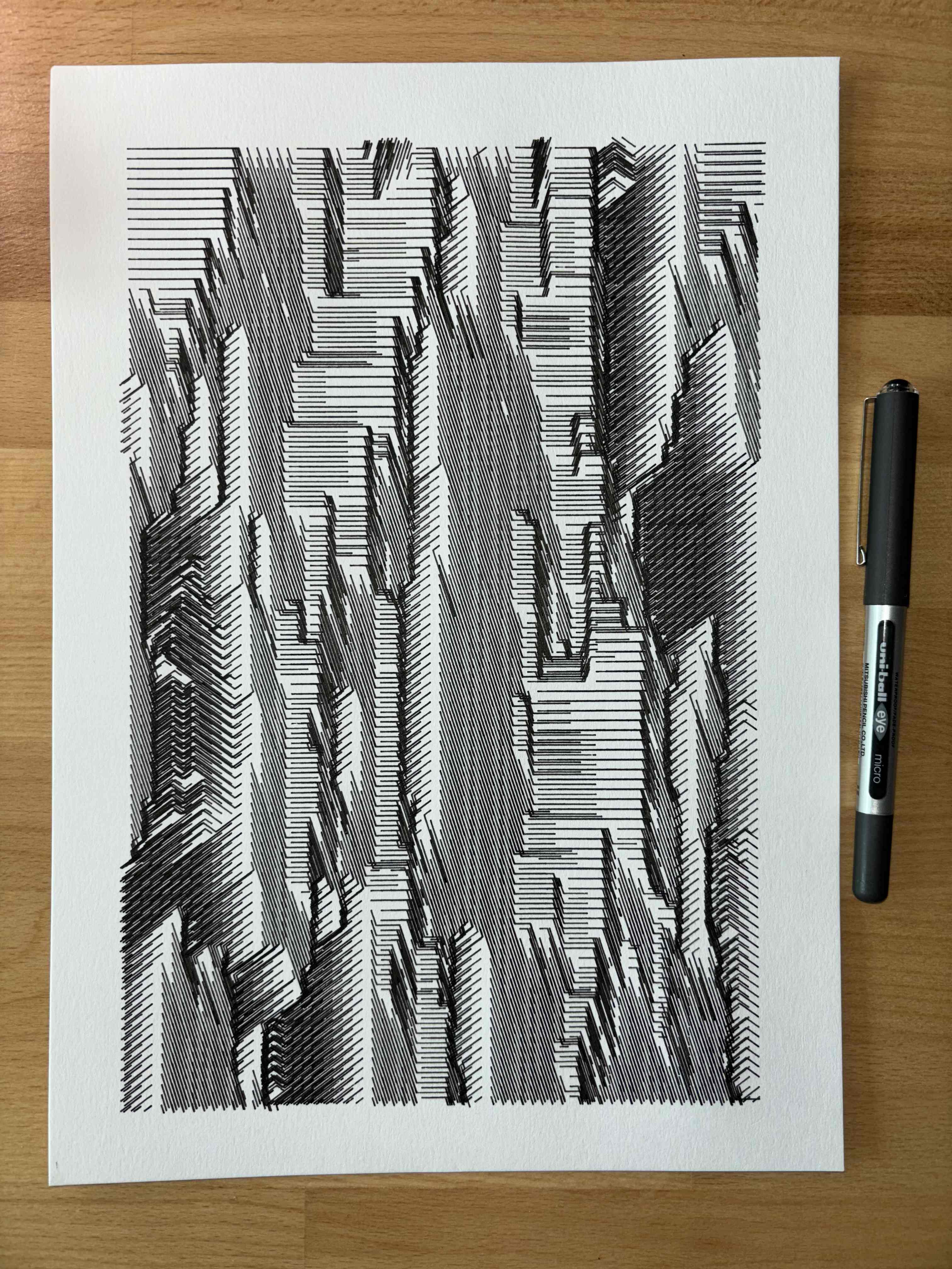 Black and white abstract drawing with vertical, jagged lines and angles on thick paper, pen resting on wooden surface