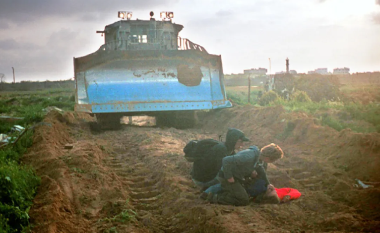 Image 1: Iranian drone inscribed with the message: 'For the revenge of Rachel Corrie'.
Image 2: US activist Rachel Corrie non-violently confronting an Israeli bulldozer to protect a Palestinian home in Gaza (2003).
Image 3: Fellow activists gathered around Rachel Corrie moments after she was fatally crushed by the bulldozer.